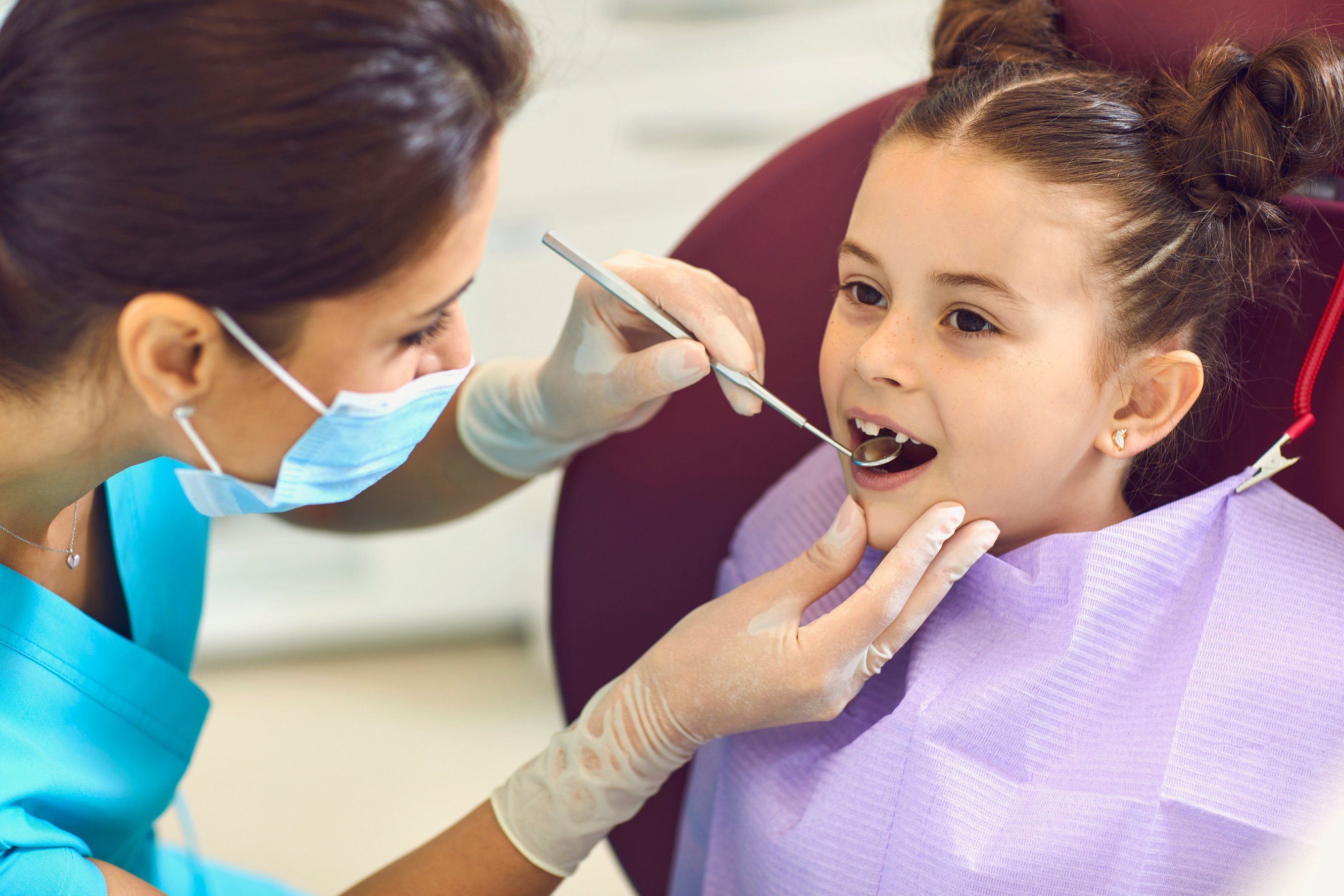 Woman Dentist Examining Smiling Child Girls Teeth with Mirror in Dental Clinic